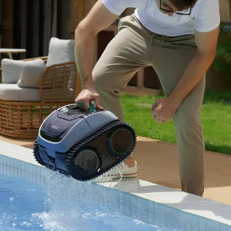 Mann hebt einen automatischen Poolreiniger aus dem Wasser am Beckenrand.